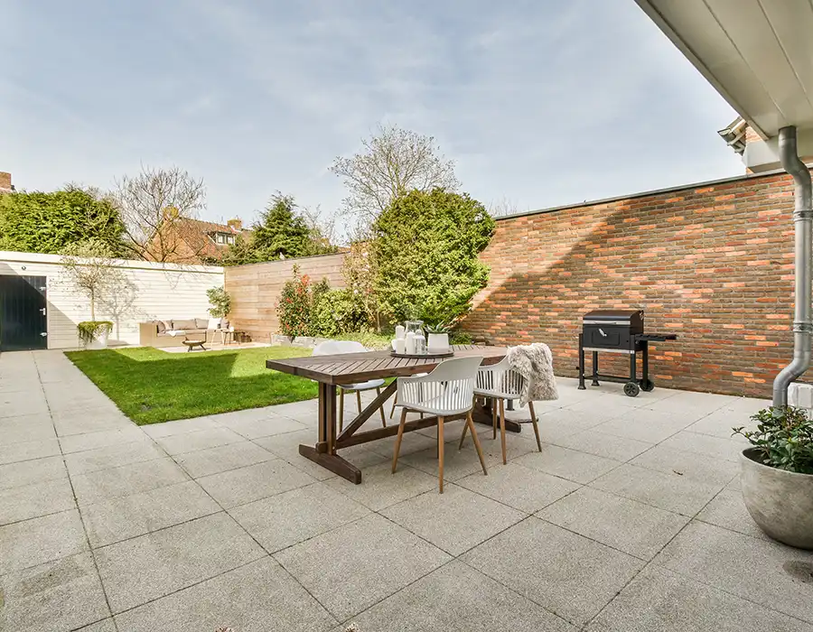 Neat paved patio with sitting area and small garden near wooden fence