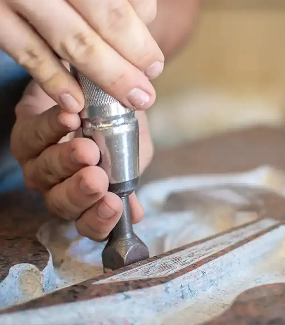 Kaukasischer Mann hämmerte einen Grabstein in einer Werkstatt mit dem Buschhammer, Arbeitskonzept